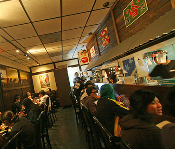 Interior of a busy ramen restaurant with customers enjoying their meals and drinks.