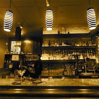 A cozy bar illuminated by a few ceiling lights.