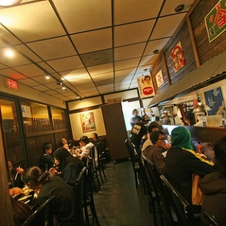  Interior of a busy ramen restaurant with customers enjoying their meals and drinks.