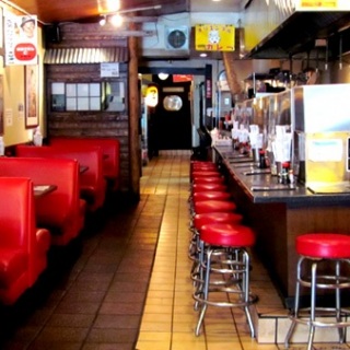 Interior of ramen restaurant with red booths and stools.