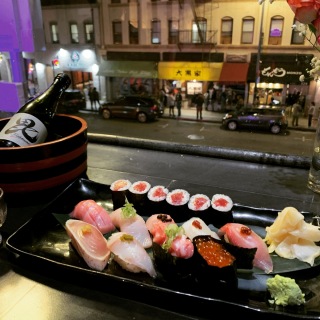A plate of sushi and a Bishamon Sake on a table in front of a window, creating a delightful culinary scene.