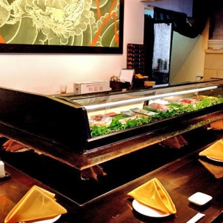 A sushi bar with a variety of sashimi on display in a large glass case.